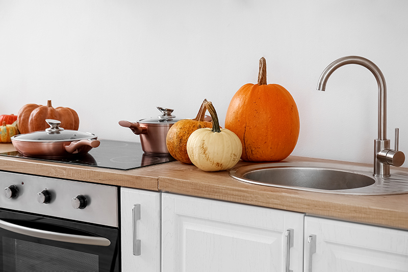 Pumpkins on kitchen counter next to sink.