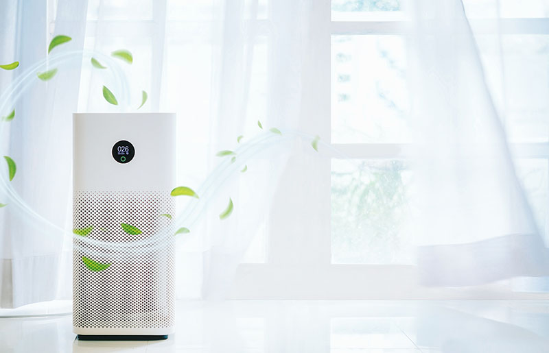 Air purifier beside an open window with fresh air currents streaming out of it.