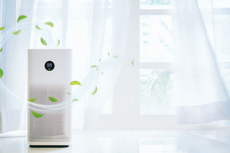 Air purifier beside an open window with fresh air currents streaming out of it.