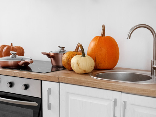 Pumpkins on kitchen counter next to sink.