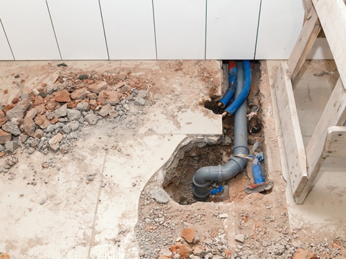 Sewer pipe under torn up tile flooring