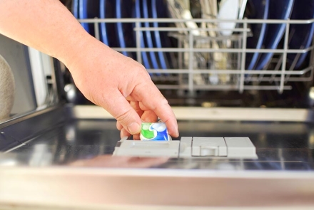 Man placing a detergent pod in dishwasher.