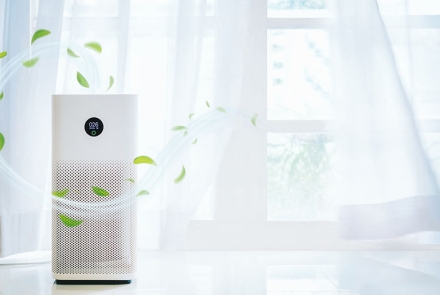 Air purifier beside an open window with fresh air currents streaming out of it.