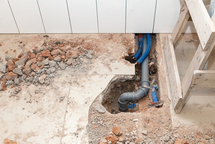 Sewer pipe under torn up tile flooring