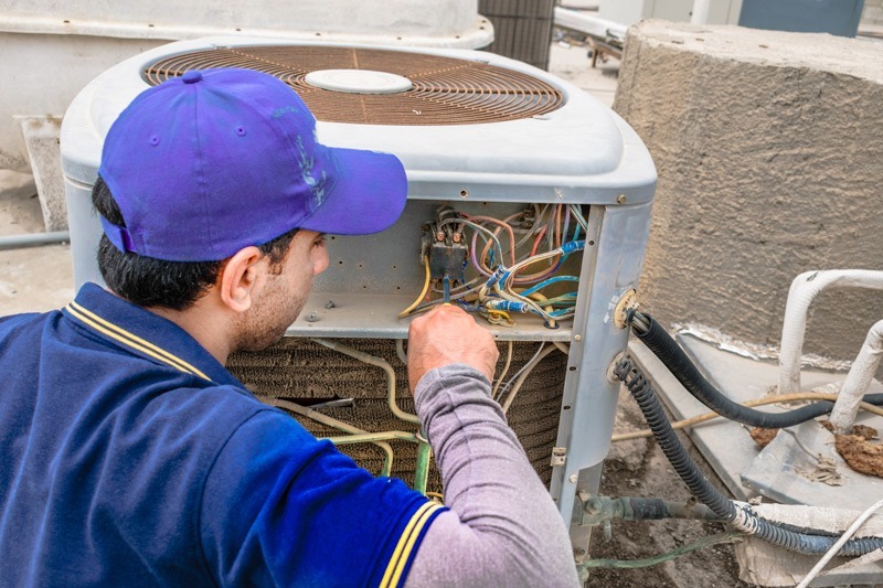 An HVAC technician maintaining an air conditioner unit.