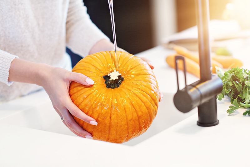 Woman washing pumpkin in a sink