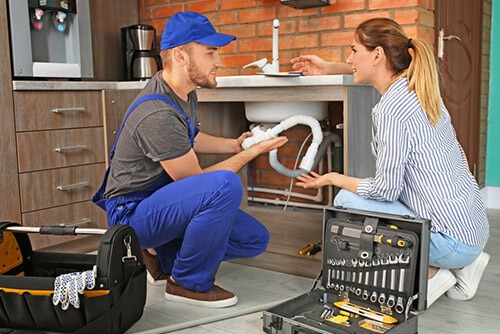 Plumber Repairing Sink While Client Watches
